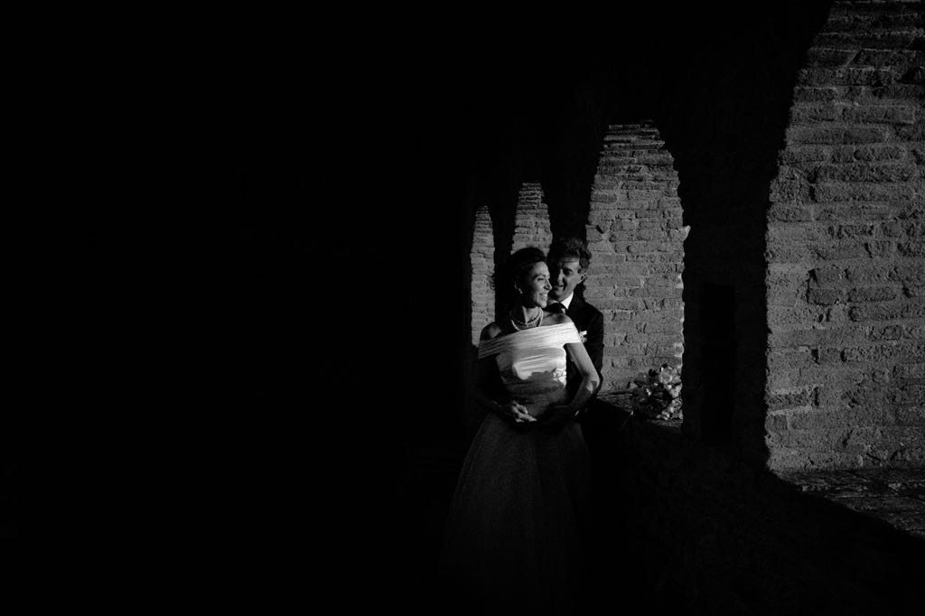 Fotografia in bianco e nero durante il servizio fotografico di matrimonio, tra gli archi del Castello di San Basilio