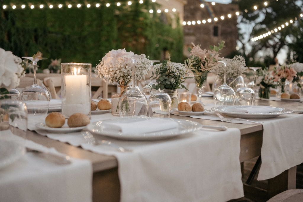 Allestimento dei tavoli per la cena all'aperto di un matrimonio nel castello di San Basilio a Marconia