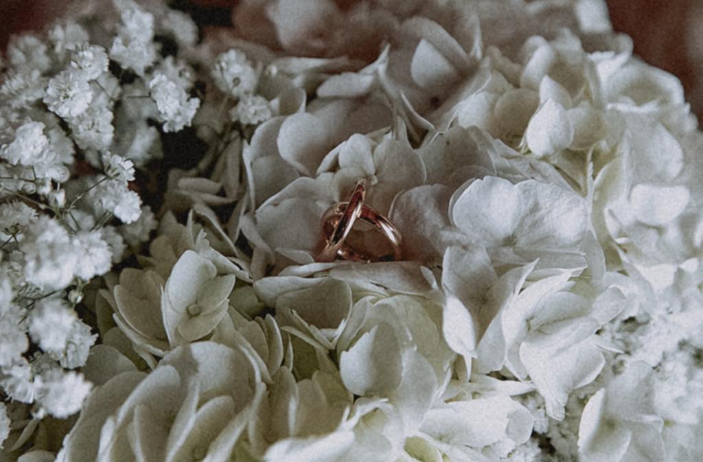 Dettagli delle fedi nuziali appoggiate sul bouquet della sposa, matrimonio da sogno Maratea