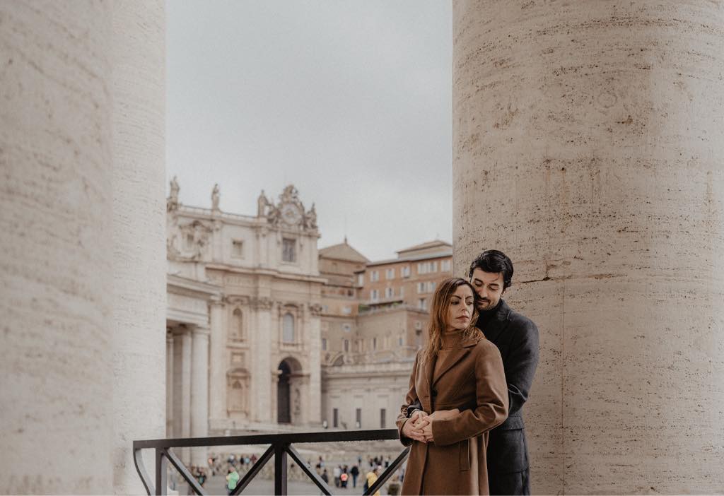 Una coppia di fidanzati che si abbraccia, con lo sfondo della Basilica di San Pietro a Roma.